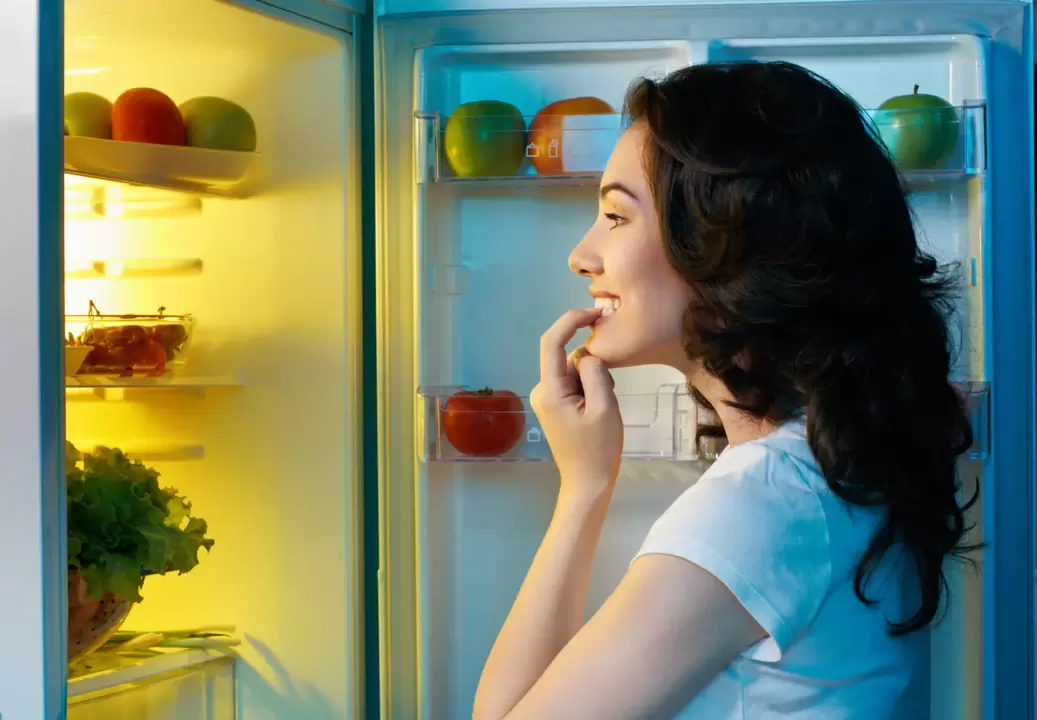 Girl looks in the fridge during fast weight loss